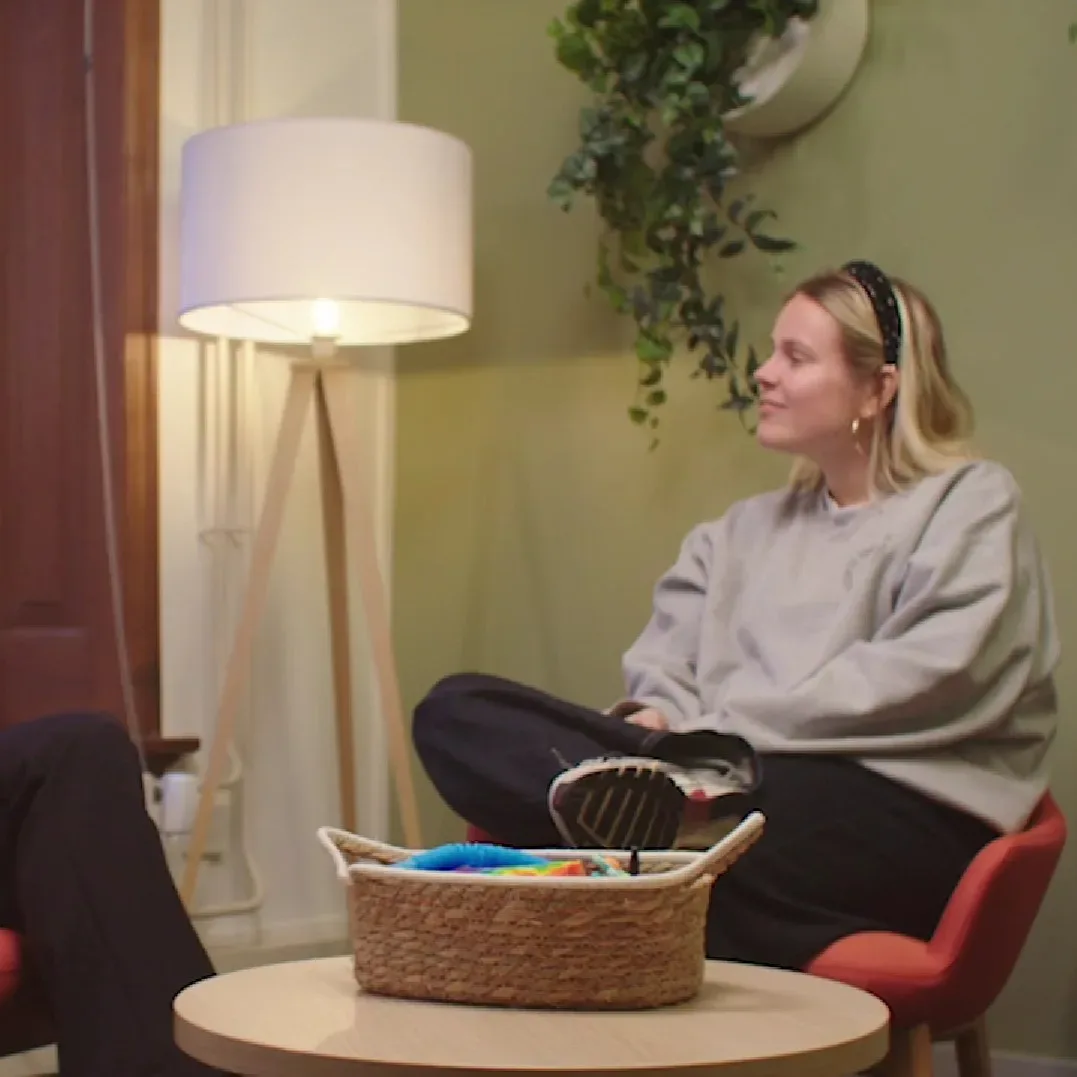 Jonge vrouw zit tegenover iemand tijdens een gesprek
